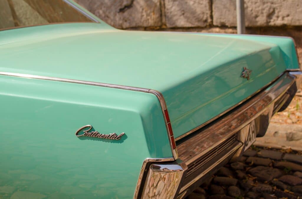 Close-up of a classic Lincoln Continental's green trunk with sunlight highlighting its features.