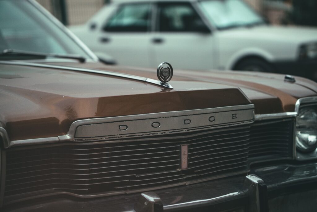 Close-up photo of a vintage Dodge car's hood, emphasizing retro design.