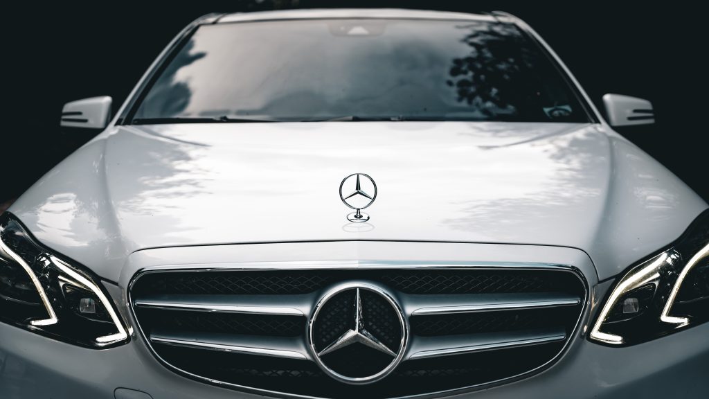 Close-up of the front of a white Mercedes E-Class showcasing the emblem and elegant design.